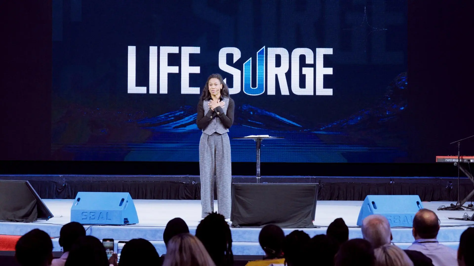 Priscilla Shirer speaking on stage at Life Surge Washington, D.C. 2025 faith and business event, with the Life Surge logo displayed behind her.