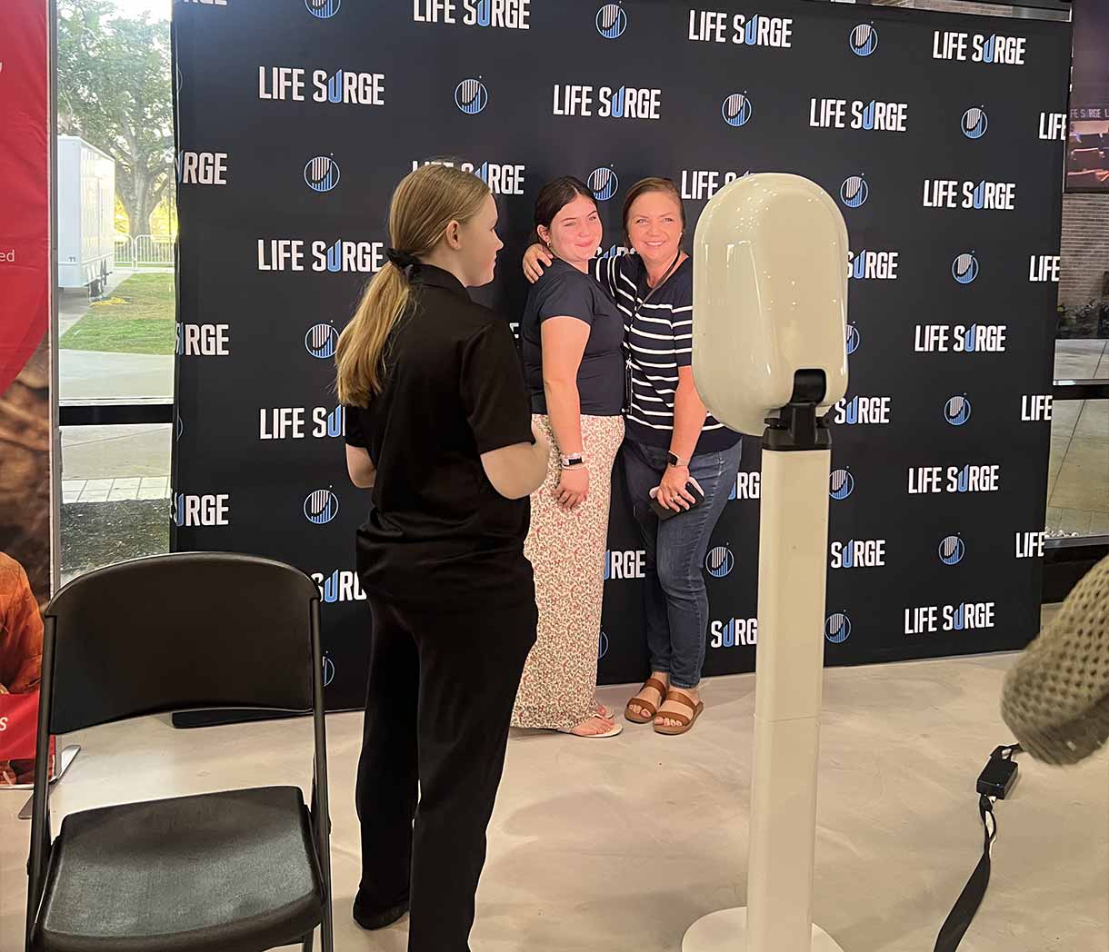 Attendees taking a photo at the Life Surge event backdrop